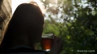 一个女人在户外喝茶的背影，夕阳透过树枝照进来